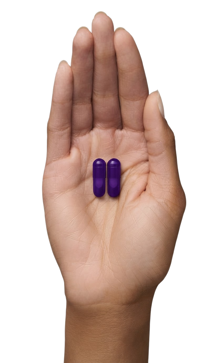 Open palm holding two purple capsules