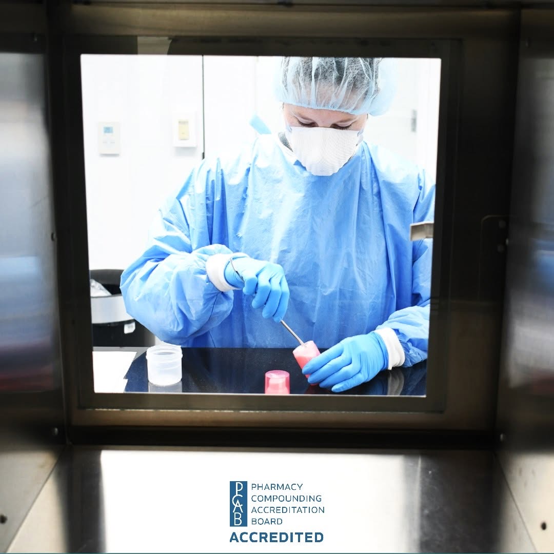 A technician compounding through the sterile pass-through window